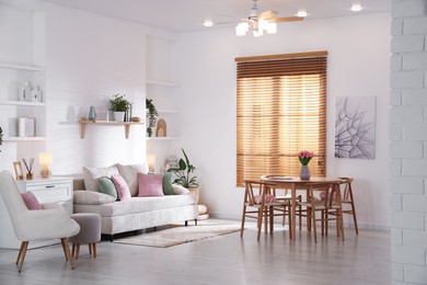 Photo of Stylish dining table with chairs and comfortable sofa in room. Interior design