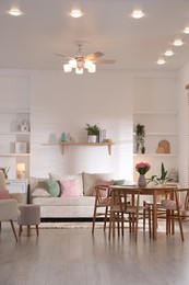 Photo of Stylish dining table with chairs and comfortable sofa in room. Interior design