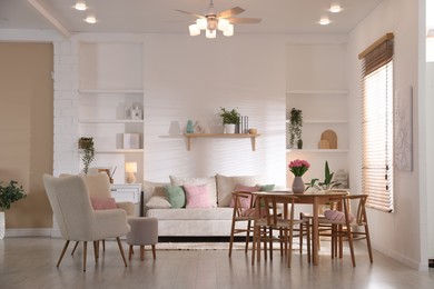Photo of Stylish dining table with chairs and comfortable sofa in room. Interior design