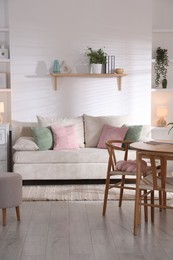 Photo of Stylish dining table with chairs and comfortable sofa in room. Interior design