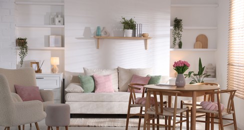 Photo of Stylish dining table with chairs and comfortable sofa in room. Interior design