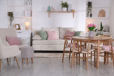 Photo of Stylish dining table with chairs and comfortable sofa in room. Interior design