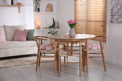 Photo of Stylish dining table with chairs and comfortable sofa in room. Interior design