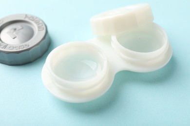 Photo of Contact lenses in case on light turquoise background, closeup