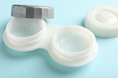 Photo of Contact lenses in case on light turquoise background, closeup