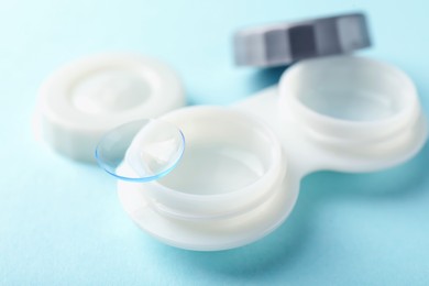 Photo of Contact lenses and case on light blue background, closeup