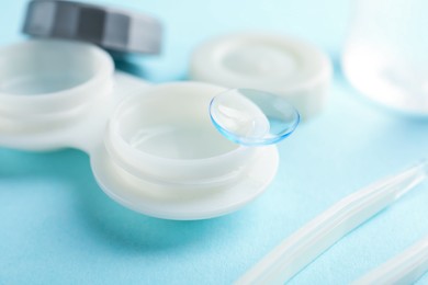 Photo of Contact lenses, case and tweezers on light blue background, closeup
