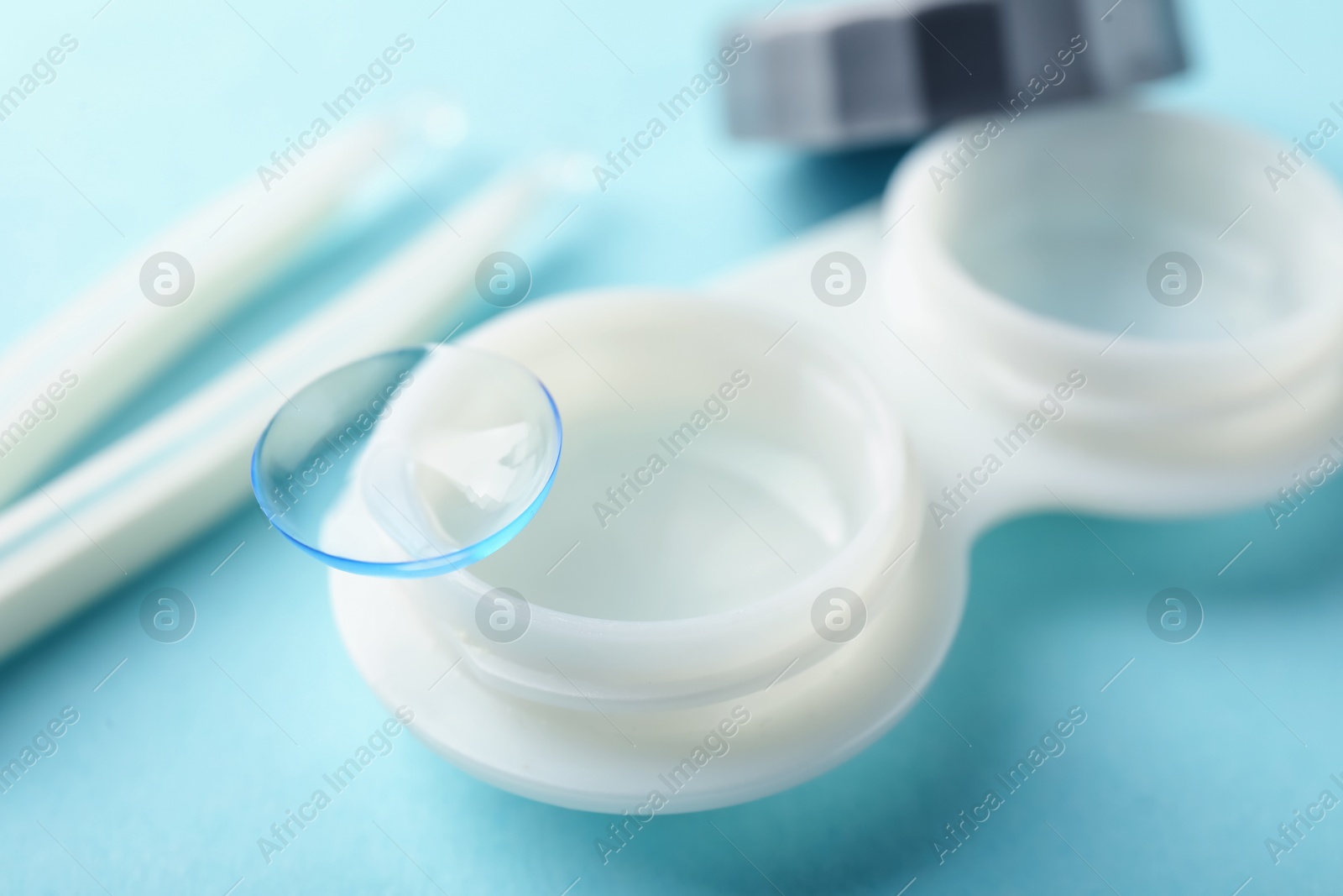 Contact lenses, case and tweezers on light blue background, closeup Photo of Contact lenses, case and tweezers on light blue background, closeup