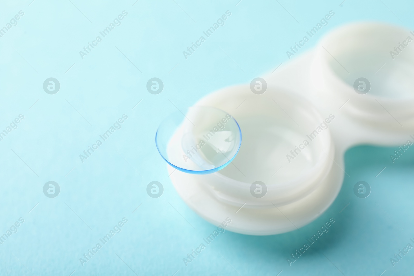 Contact lenses and case on light turquoise background, closeup. Space for text Photo of Contact lenses and case on light turquoise background, closeup. Space for text