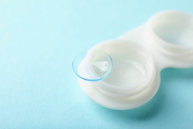 Photo of Contact lenses and case on light turquoise background, closeup. Space for text
