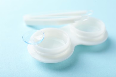 Photo of Contact lenses, case and tweezers on light blue background, closeup