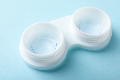 Photo of Contact lens in case on light blue background, closeup