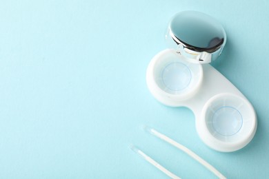 Photo of Contact lenses in case and tweezers on light turquoise background, flat lay. Space for text