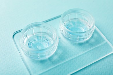 Photo of Contact lenses in case on light turquoise background, closeup