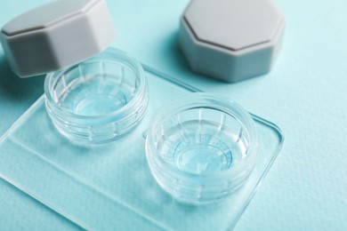 Photo of Contact lenses in case on light turquoise background, closeup