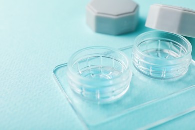 Photo of Contact lenses in case on light turquoise background, closeup