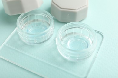Photo of Contact lenses in case on light turquoise background, closeup