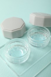 Photo of Contact lenses in case on light turquoise background, closeup
