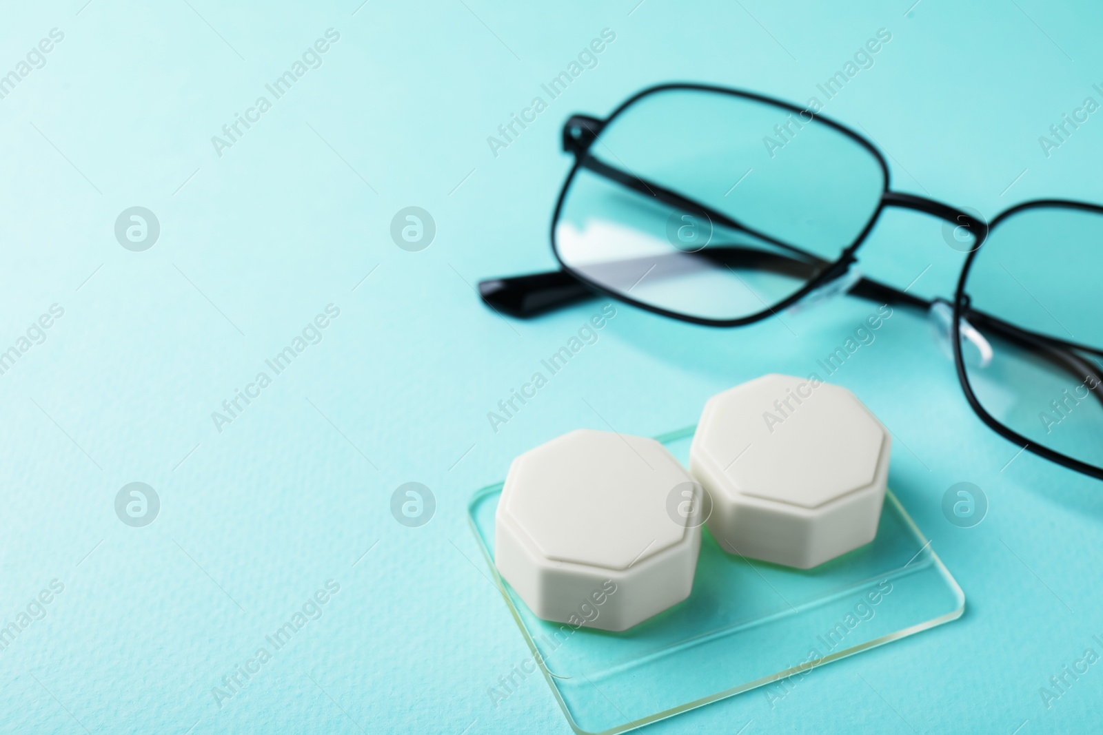 Contact lens case and glasses on turquoise background, closeup. Space for text Photo of Contact lens case and glasses on turquoise background, closeup. Space for text