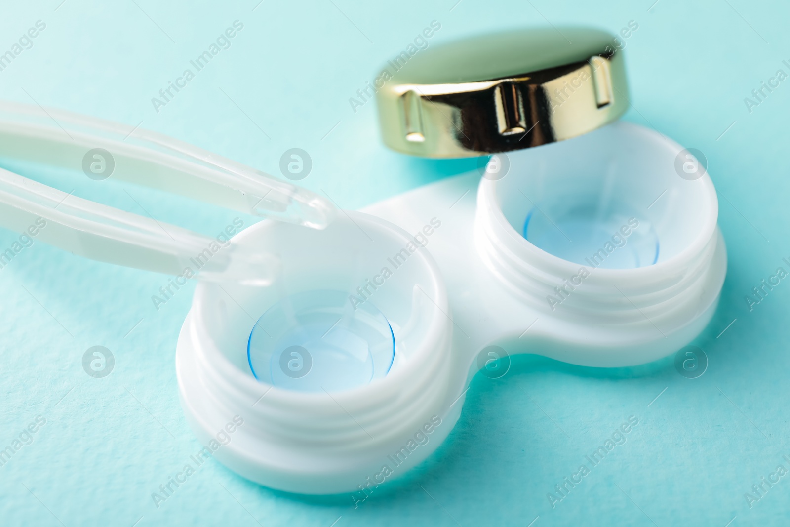 Contact lenses in case and tweezers on turquoise background, closeup Photo of Contact lenses in case and tweezers on turquoise background, closeup