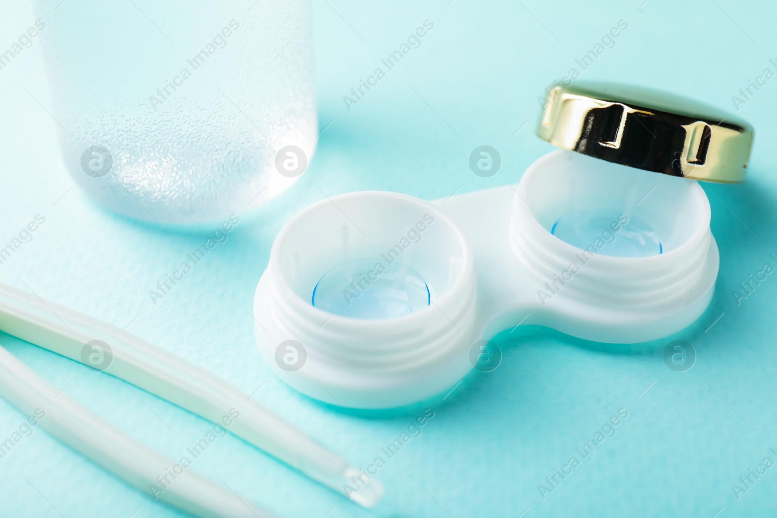 Contact lenses in case and tweezers on turquoise background, closeup Photo of Contact lenses in case and tweezers on turquoise background, closeup