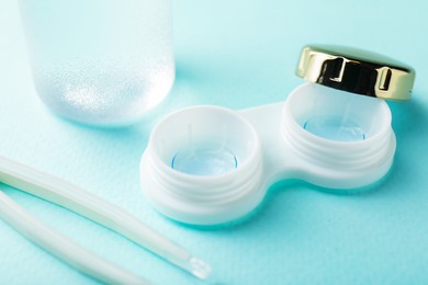 Photo of Contact lenses in case and tweezers on turquoise background, closeup