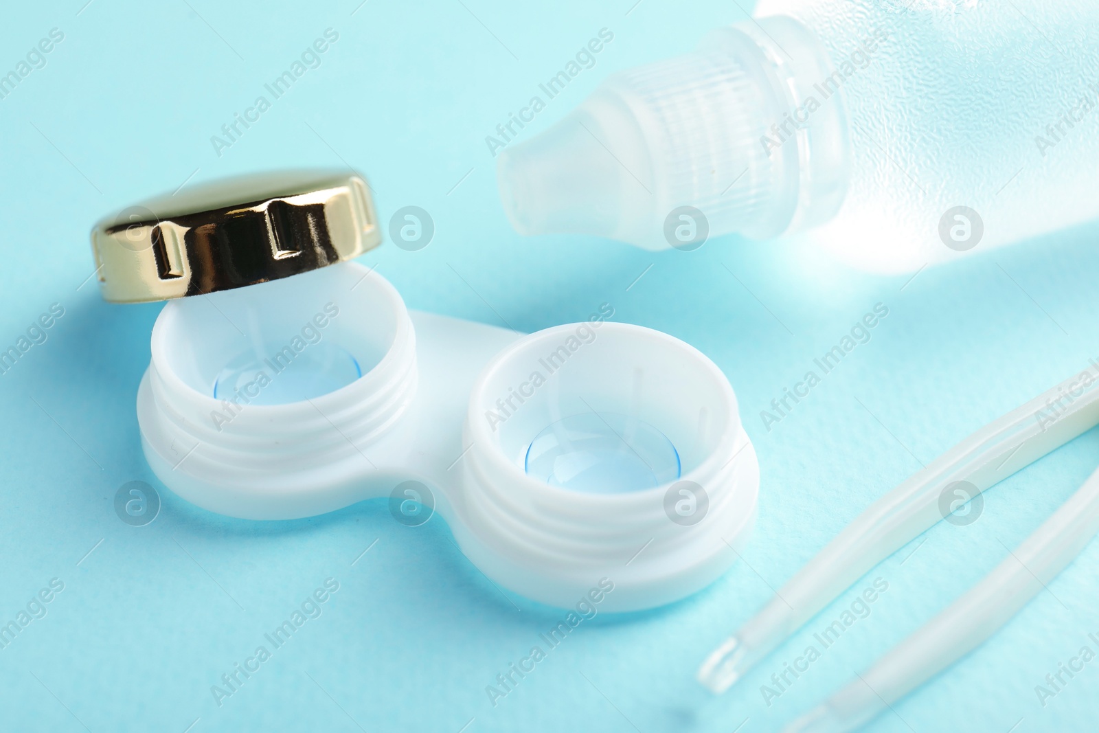 Contact lenses in case, solution and tweezers on light blue background, closeup Photo of Contact lenses in case, solution and tweezers on light blue background, closeup