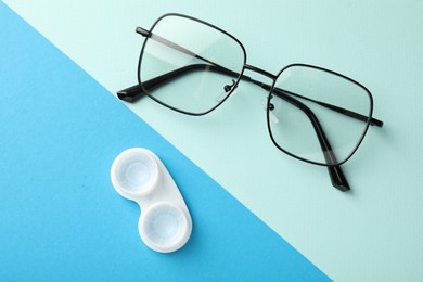 Photo of Contact lenses in case and glasses on color background, flat lay