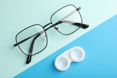 Photo of Contact lenses in case and glasses on color background, flat lay