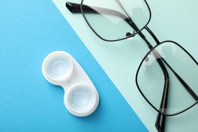 Photo of Contact lenses in case and glasses on color background, flat lay