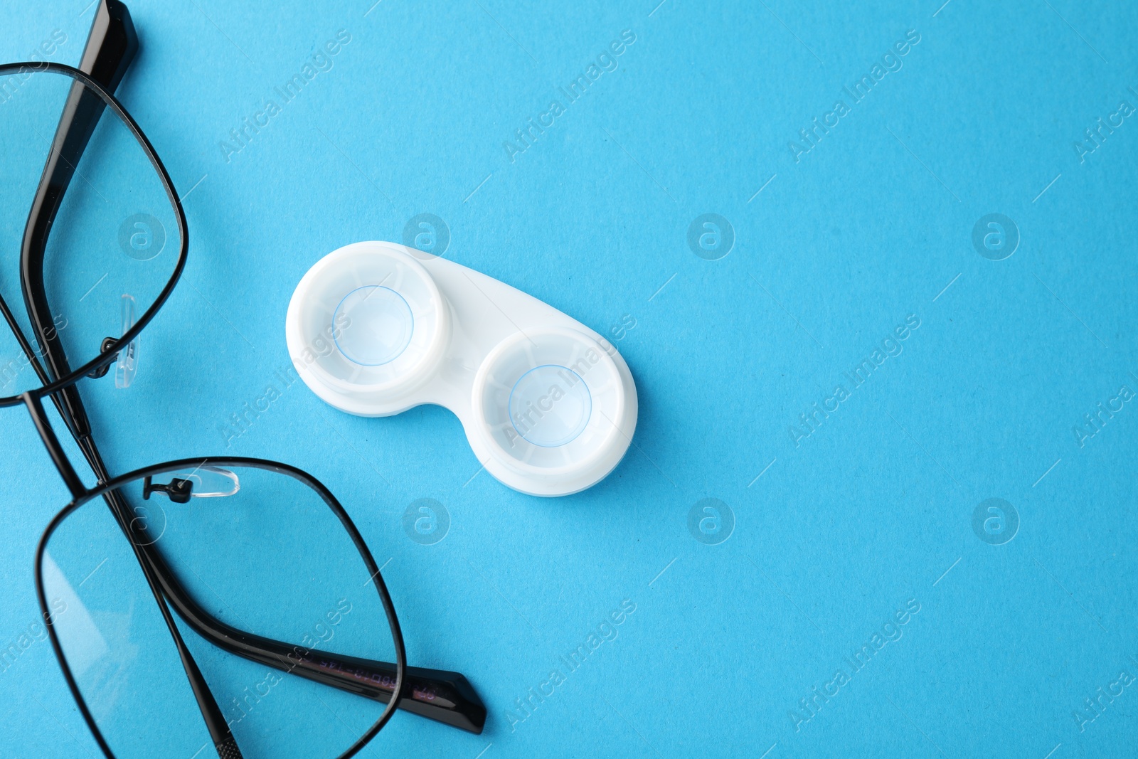 Contact lenses in case and glasses on blue background, flat lay. Space for text Photo of Contact lenses in case and glasses on blue background, flat lay. Space for text