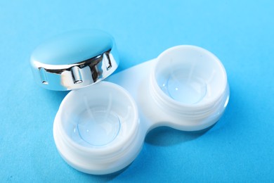 Photo of Contact lenses in case on blue background, closeup