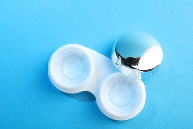Photo of Contact lenses in case on blue background, top view