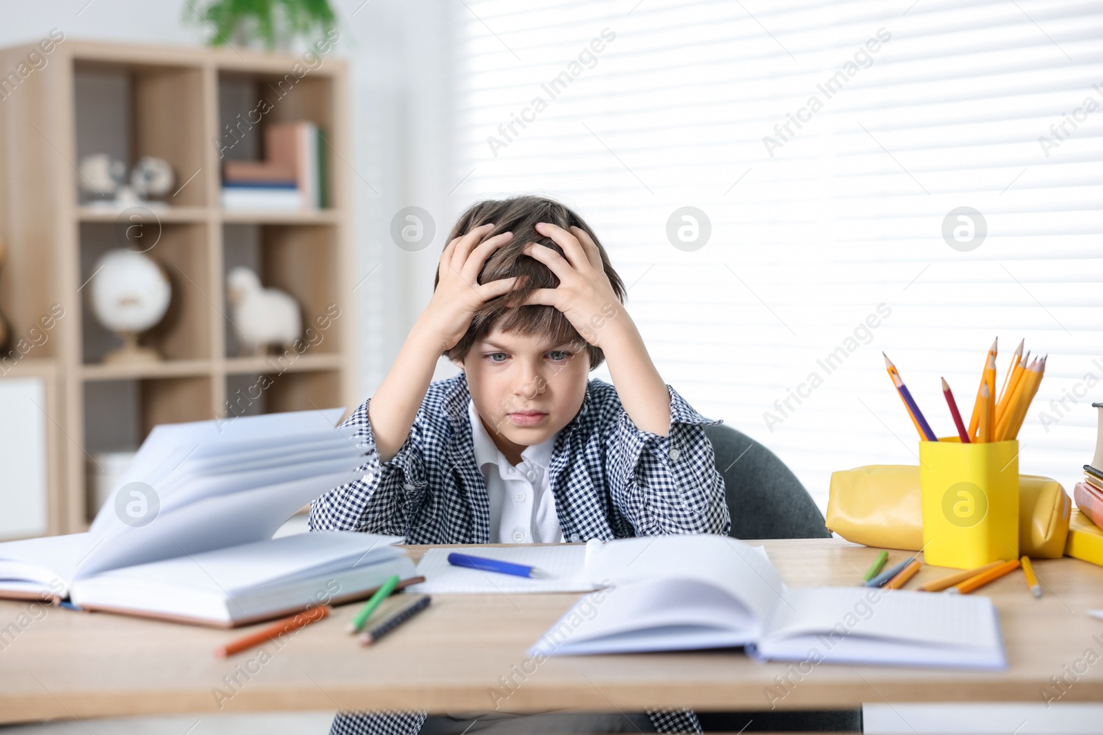 Tired little boy doing homework at table indoors Photo of Tired little boy doing homework at table indoors