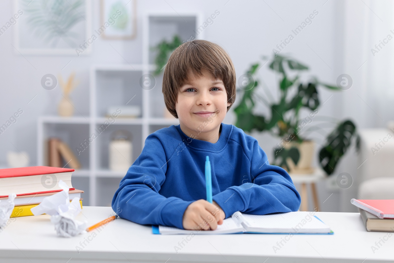 Cute little boy doing homework at desk indoors Photo of Cute little boy doing homework at desk indoors