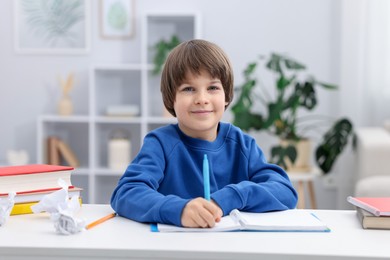 Photo of Cute little boy doing homework at desk indoors