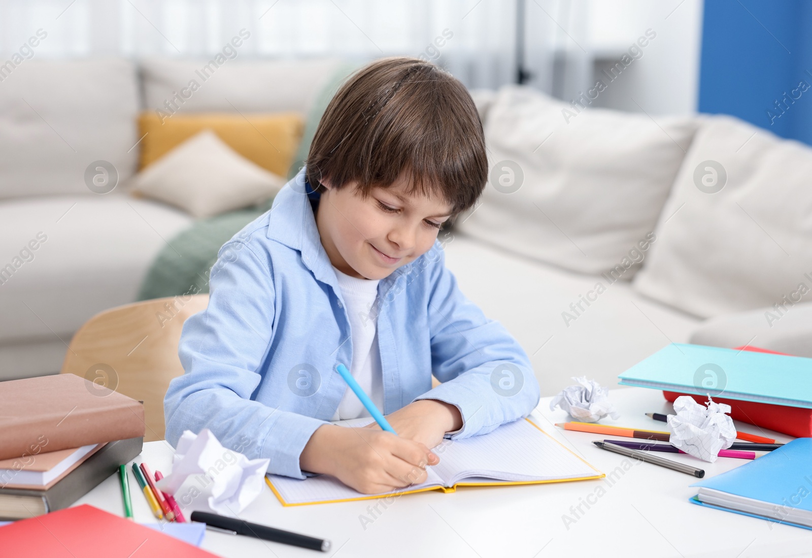 Cute little boy doing homework at table indoors Photo of Cute little boy doing homework at table indoors