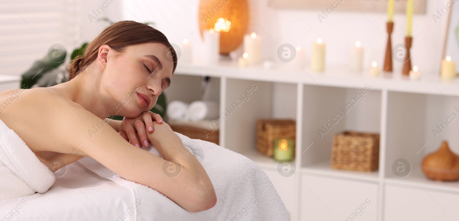 Beautiful woman relaxing on massage couch in spa salon. Space for text Photo of Beautiful woman relaxing on massage couch in spa salon. Space for text