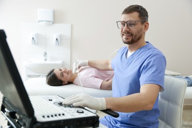 Photo of Sonographer conducting ultrasound examination of woman's thyroid gland in clinic
