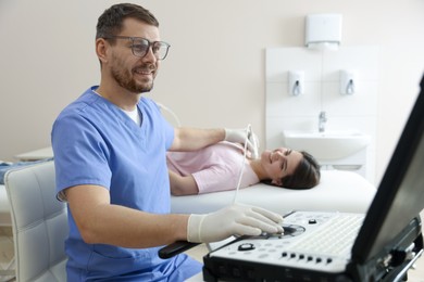 Photo of Sonographer conducting ultrasound examination of woman's thyroid gland in clinic