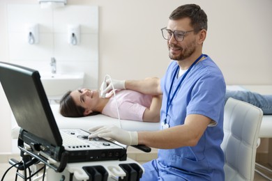 Photo of Sonographer conducting ultrasound examination of woman's thyroid gland in clinic