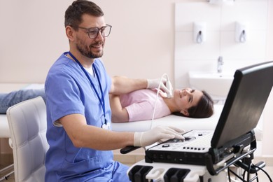 Photo of Sonographer conducting ultrasound examination of woman's thyroid gland in clinic
