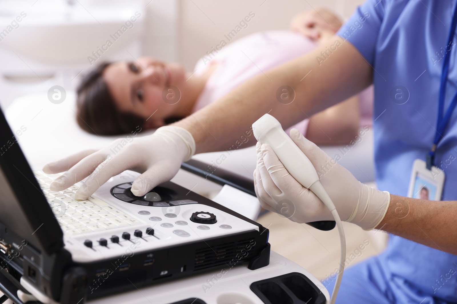 Sonographer with ultrasound transducer and woman waiting for examination in clinic, selective focus Photo of Sonographer with ultrasound transducer and woman waiting for examination in clinic, selective focus