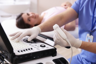 Photo of Sonographer with ultrasound transducer and woman waiting for examination in clinic, selective focus