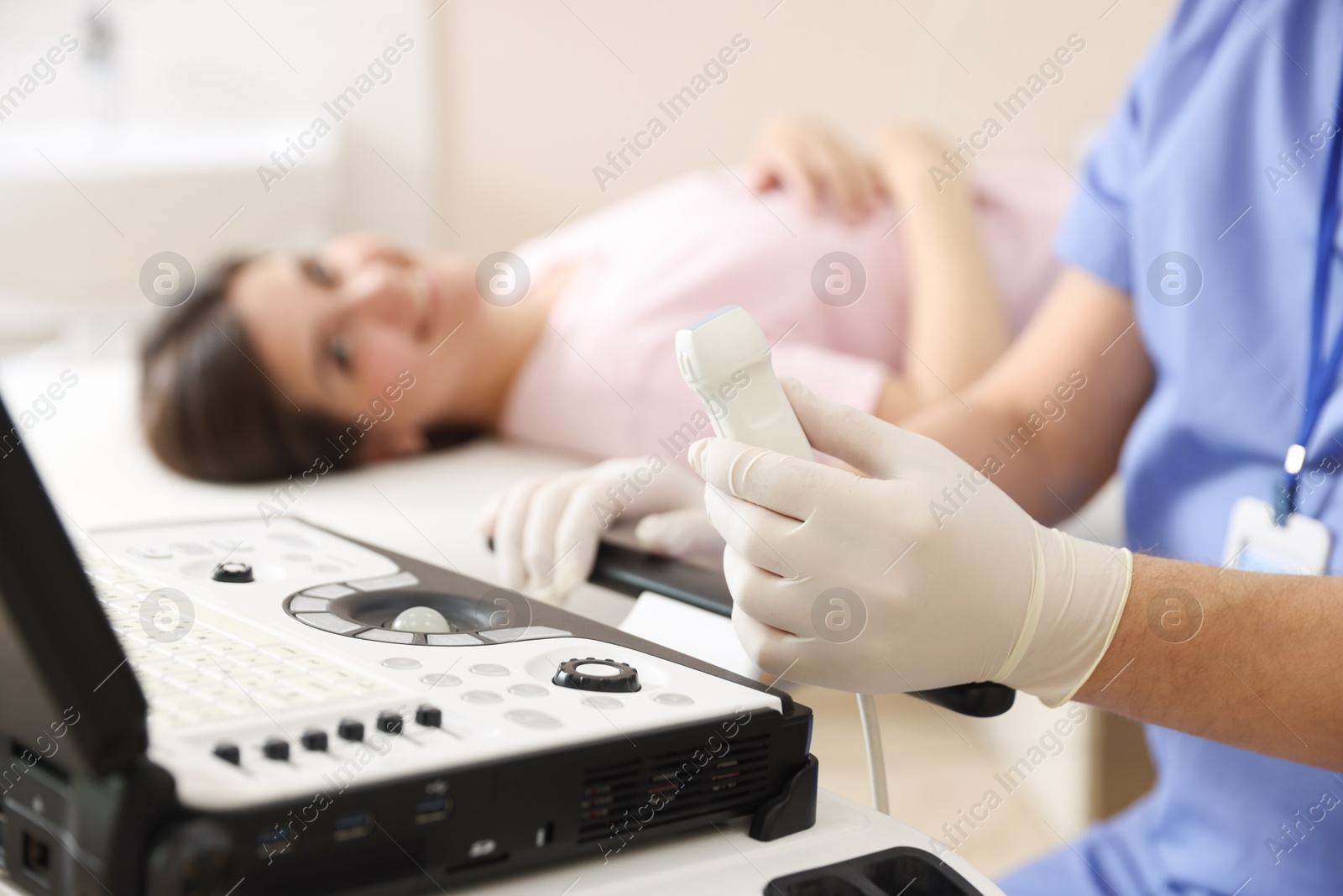 Sonographer with ultrasound transducer and woman waiting for examination in clinic, selective focus Photo of Sonographer with ultrasound transducer and woman waiting for examination in clinic, selective focus