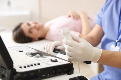 Photo of Sonographer with ultrasound transducer and woman waiting for examination in clinic, selective focus