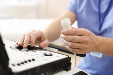Photo of Sonographer with transducer and ultrasound machine in clinic, closeup