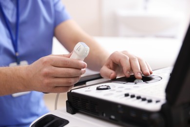 Photo of Sonographer with transducer and ultrasound machine in clinic, closeup