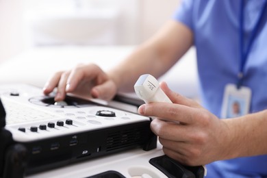 Photo of Sonographer with transducer and ultrasound machine in clinic, closeup