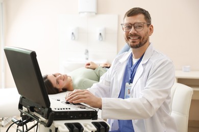 Photo of Sonographer with ultrasound machine and woman waiting for examination in clinic, selective focus